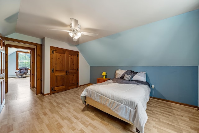 bedroom featuring vaulted ceiling, a closet, light wood-type flooring, and baseboards