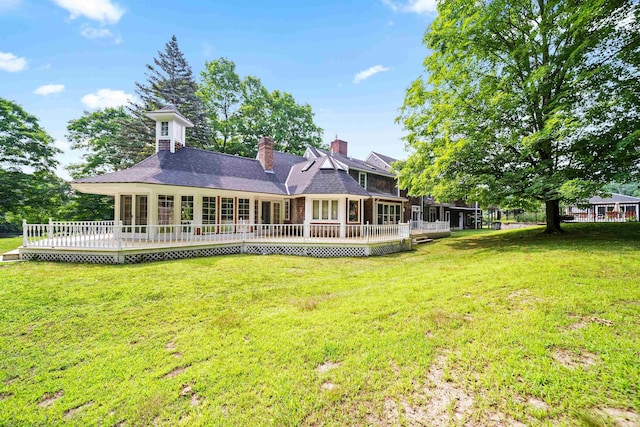 back of house with a sunroom, a chimney, a yard, and a deck