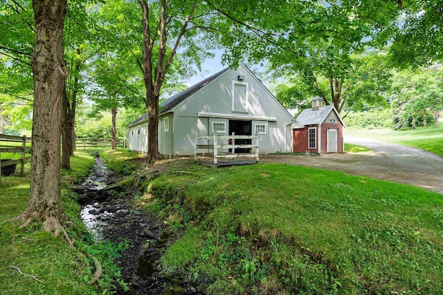 view of front facade with a front lawn, an outbuilding, fence, and dirt driveway