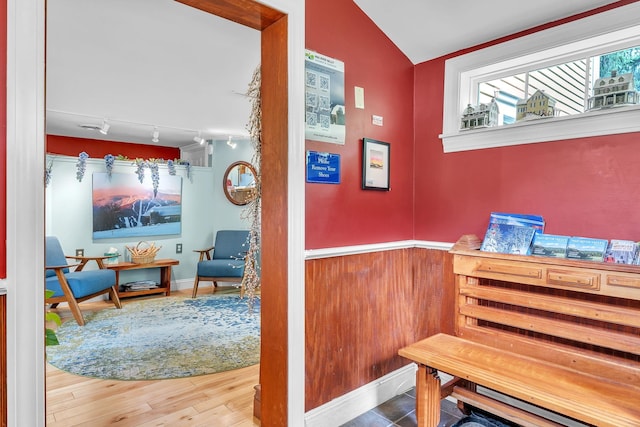 hall with lofted ceiling, hardwood / wood-style floors, and track lighting