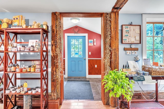 entrance foyer with lofted ceiling, a wealth of natural light, and wooden walls