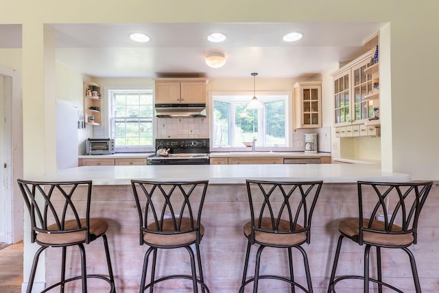 kitchen featuring electric range, a kitchen breakfast bar, pendant lighting, and kitchen peninsula