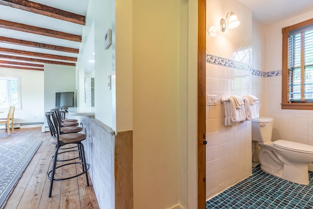 bathroom featuring beamed ceiling, toilet, wood-type flooring, and tile walls