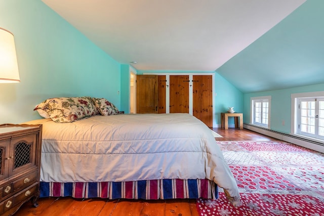 bedroom with hardwood / wood-style floors, a baseboard radiator, and vaulted ceiling