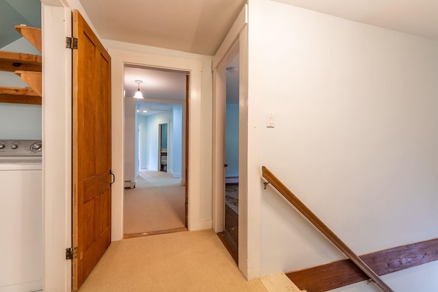 hall featuring washer / dryer, light colored carpet, and a baseboard radiator