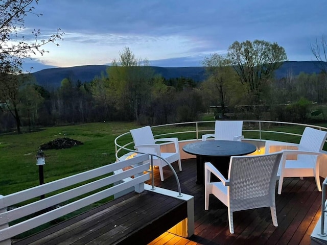 wooden terrace featuring a mountain view and a lawn