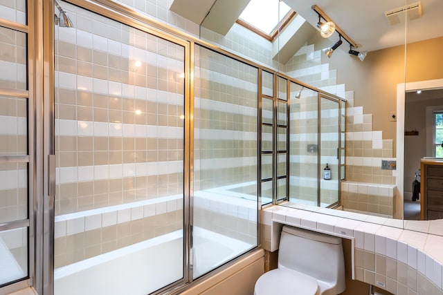 bathroom featuring toilet, lofted ceiling, and bath / shower combo with glass door