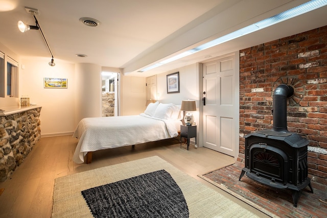 bedroom featuring a wood stove and light hardwood / wood-style flooring