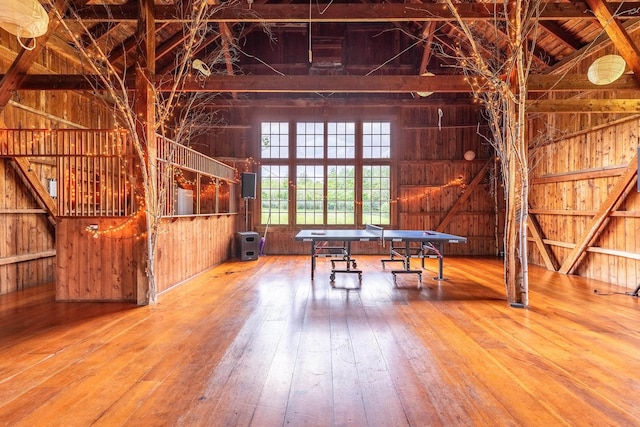 game room with high vaulted ceiling, beamed ceiling, and wood walls