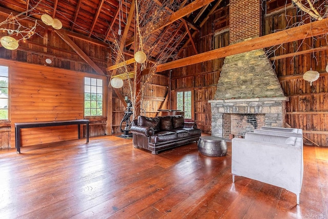 unfurnished living room with hardwood / wood-style flooring, wooden walls, high vaulted ceiling, and beamed ceiling