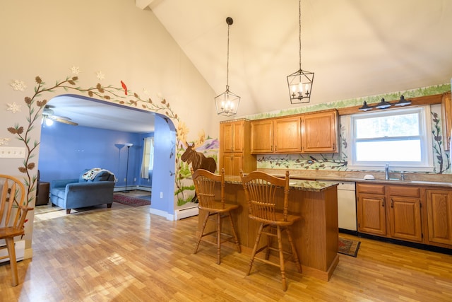 kitchen with decorative light fixtures, dishwasher, sink, a breakfast bar area, and a center island