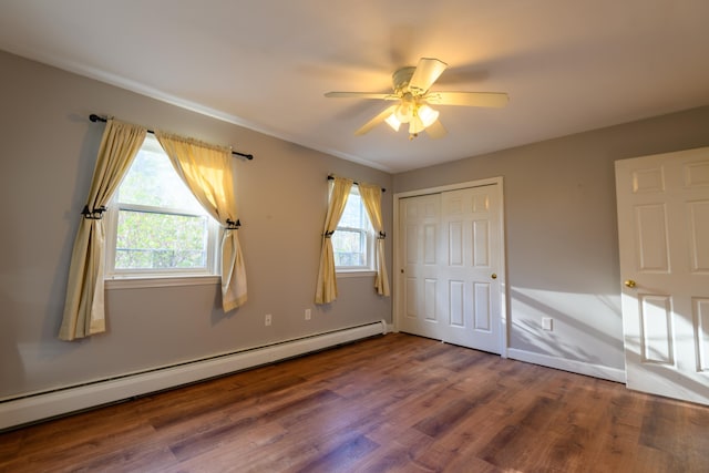 unfurnished bedroom with baseboard heating, ceiling fan, hardwood / wood-style floors, and a closet