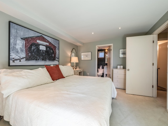 bedroom with ensuite bathroom and light colored carpet