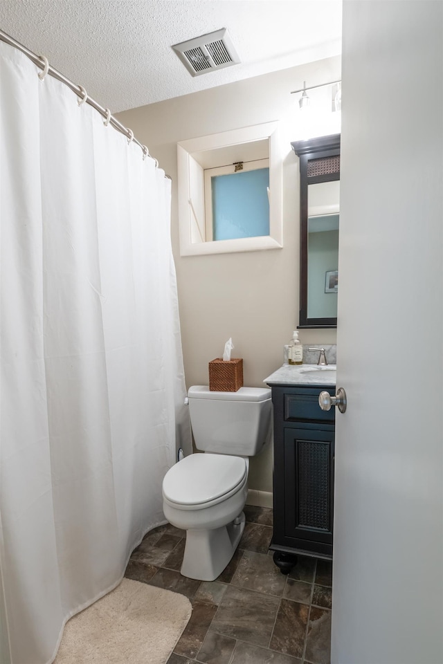 bathroom with vanity, a textured ceiling, and toilet