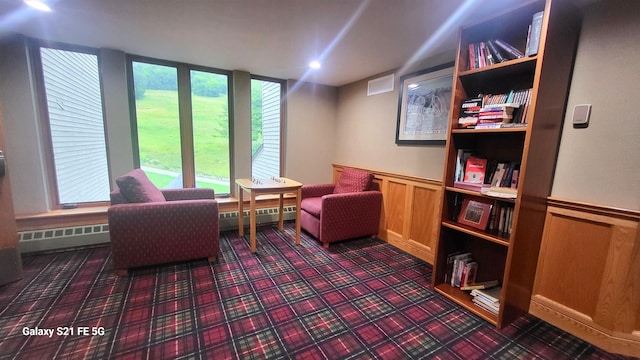 sitting room featuring a baseboard heating unit and wooden walls