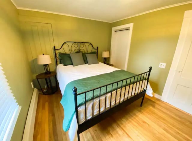 bedroom with hardwood / wood-style flooring, a closet, and ornamental molding