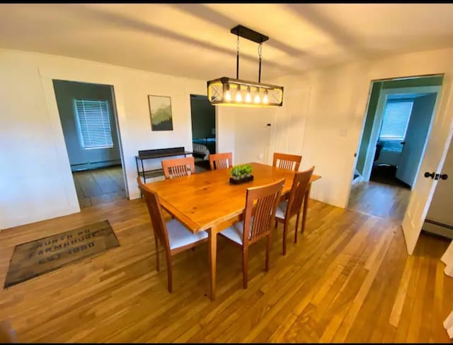 dining area with a baseboard heating unit and hardwood / wood-style flooring