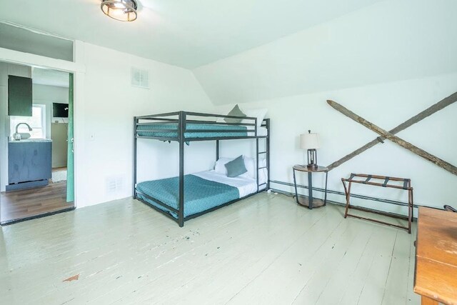 bedroom with lofted ceiling, wood-type flooring, and multiple windows