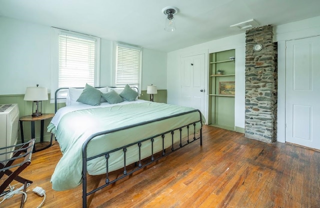 bedroom with hardwood / wood-style flooring and decorative columns