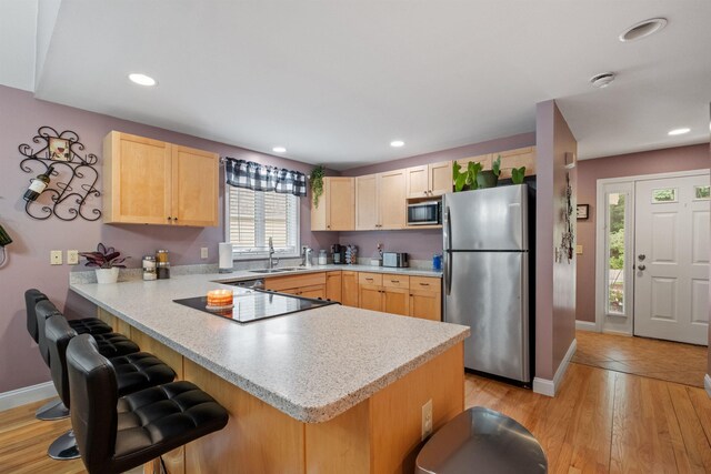 kitchen with sink, kitchen peninsula, light brown cabinets, and stainless steel appliances
