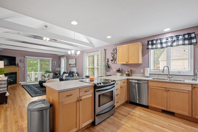 kitchen featuring an inviting chandelier, vaulted ceiling, sink, stainless steel appliances, and kitchen peninsula
