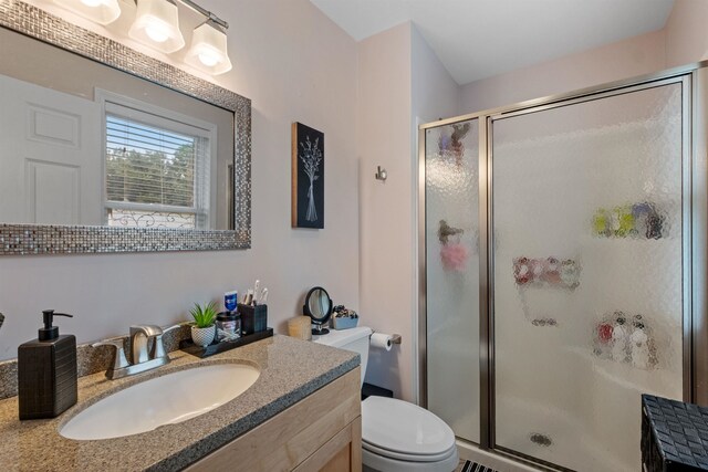 bathroom featuring vanity, toilet, and a shower with door