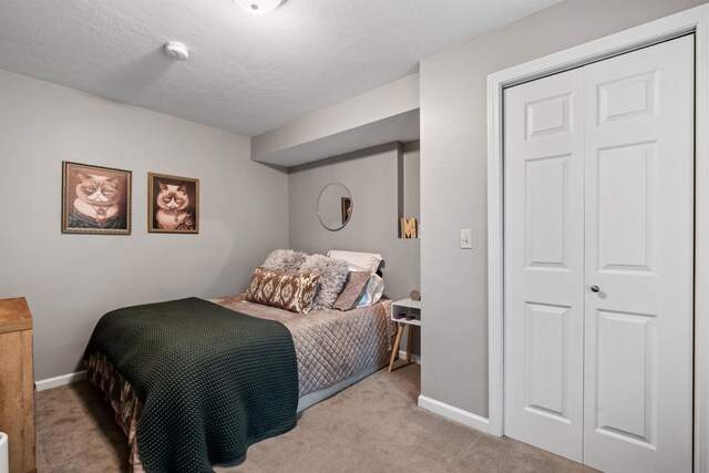 bedroom with a textured ceiling, a closet, and light colored carpet