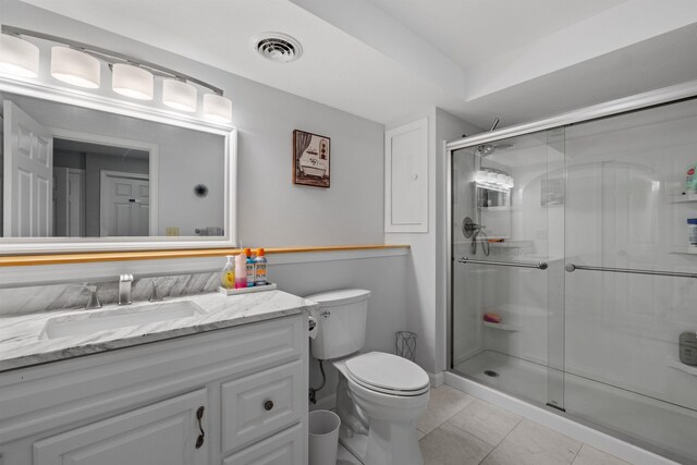 bathroom with tile patterned floors, vanity, toilet, and a shower with door