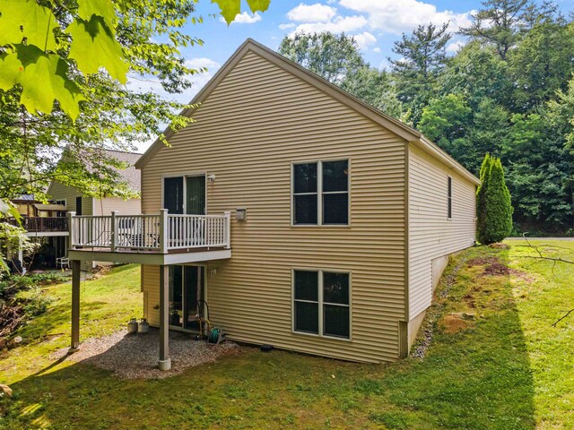 rear view of house featuring a deck and a lawn