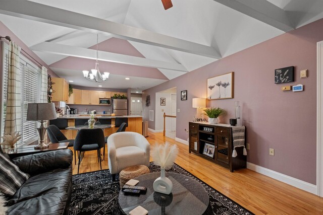 living room with light hardwood / wood-style floors, lofted ceiling with beams, and a notable chandelier