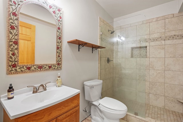 bathroom with vanity, tiled shower, and toilet