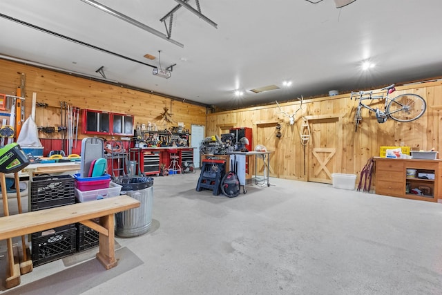 garage featuring a garage door opener, wooden walls, and a workshop area