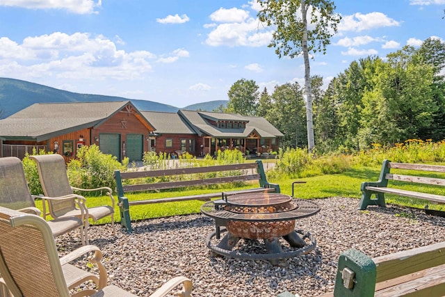 view of home's community with a mountain view, a yard, and an outdoor fire pit