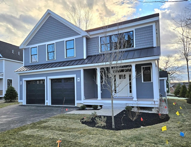 view of front of home featuring covered porch, a garage, and a yard