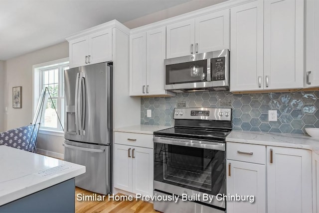 kitchen with stainless steel appliances, decorative backsplash, and white cabinets