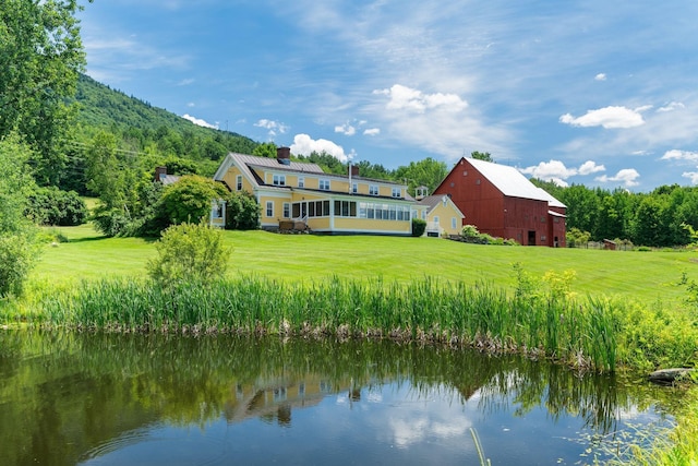 rear view of house featuring a lawn and a water and mountain view