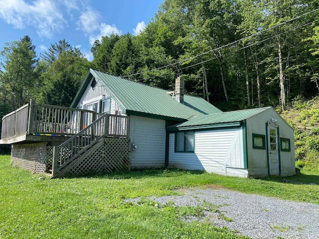 back of property featuring a deck and a lawn