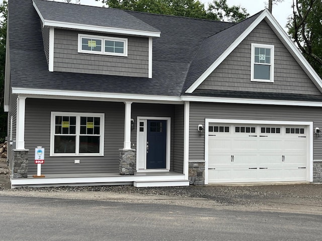 craftsman inspired home featuring a garage, stone siding, roof with shingles, and a porch