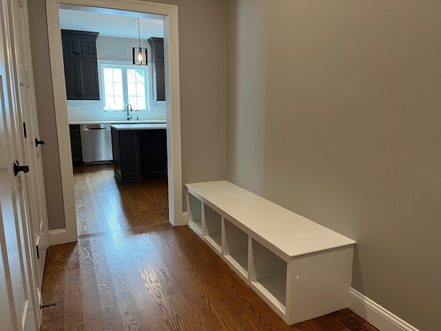 mudroom with dark wood-style floors, baseboards, and a sink