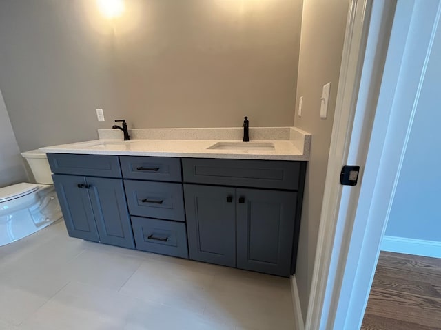 bathroom featuring double vanity, a sink, toilet, and tile patterned floors