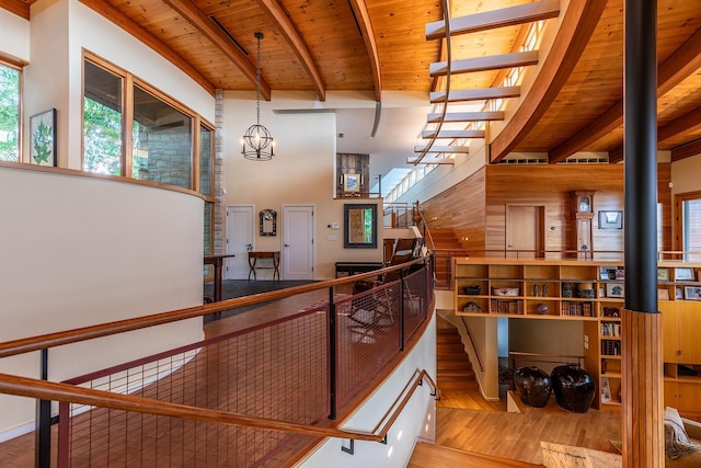 interior space featuring beamed ceiling, a high ceiling, hardwood / wood-style flooring, a chandelier, and wooden ceiling