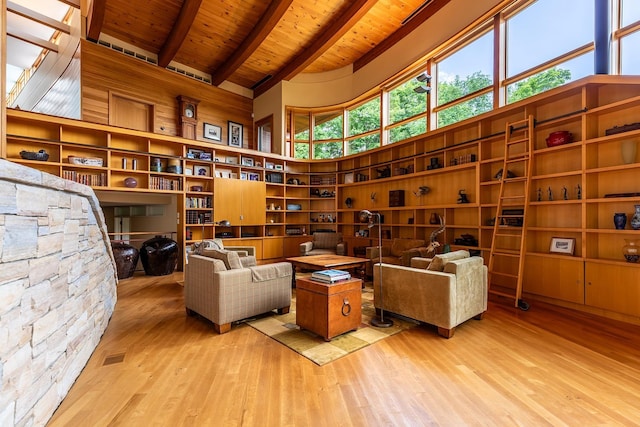 sitting room with beam ceiling, wood-type flooring, wood ceiling, and a high ceiling