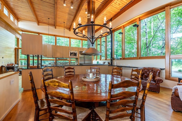 dining room featuring beam ceiling, a chandelier, and light wood-type flooring