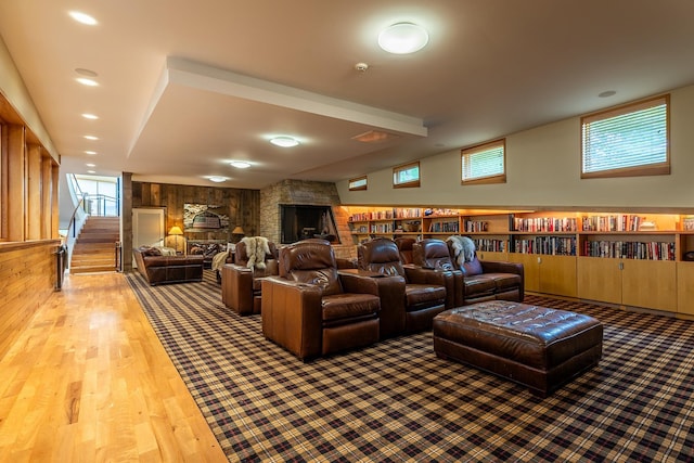 cinema with hardwood / wood-style floors, vaulted ceiling, wood walls, and a fireplace