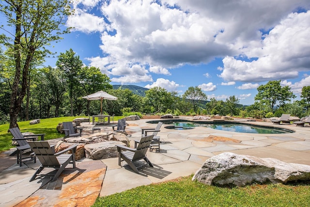 view of pool featuring a lawn, a patio area, and a mountain view