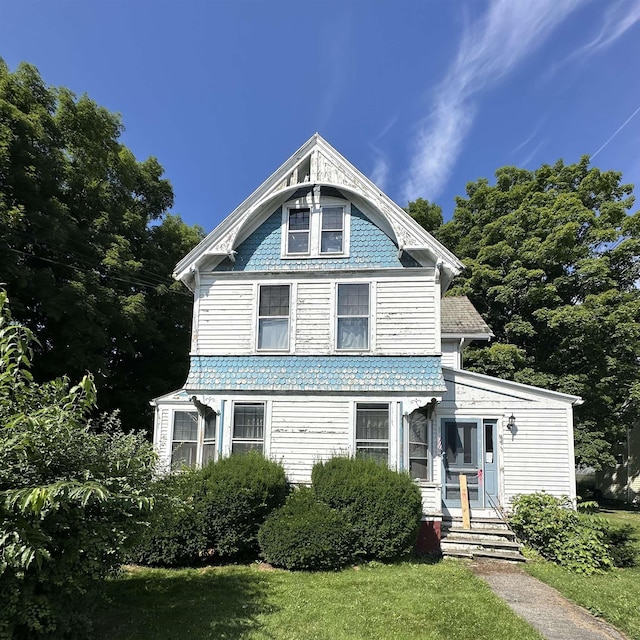 victorian-style house with a front lawn