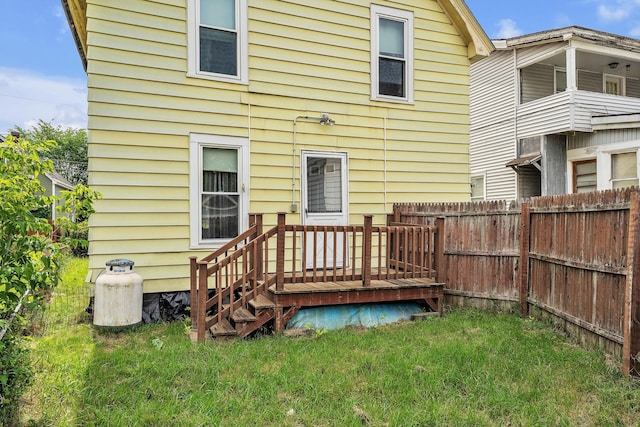 rear view of property featuring a wooden deck and a lawn