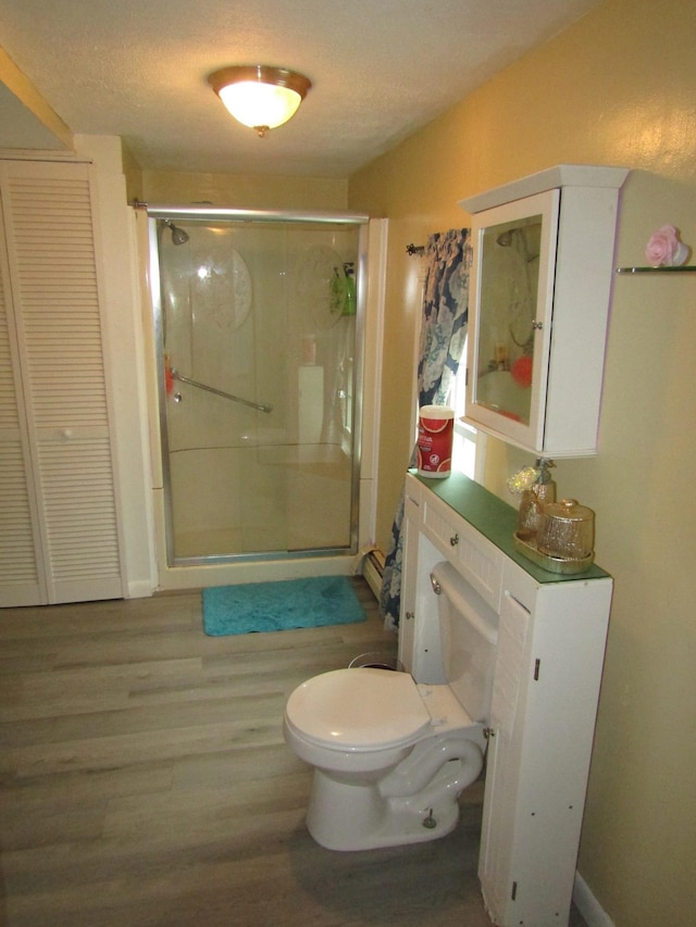 bathroom featuring a shower with shower door, wood-type flooring, toilet, and a textured ceiling