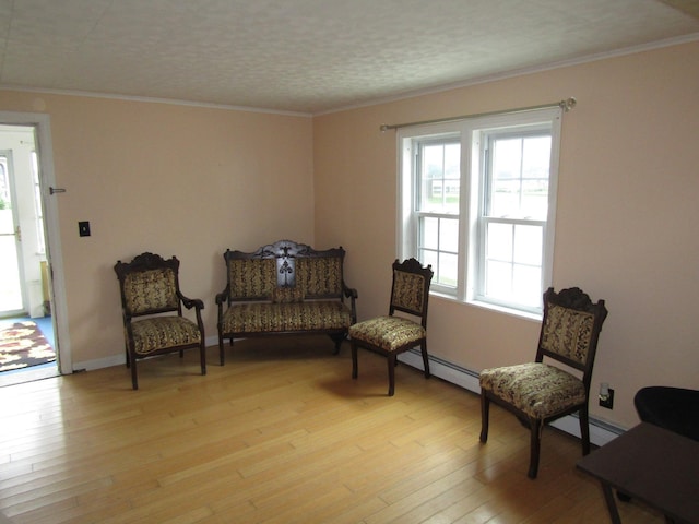 living area featuring baseboard heating, crown molding, and light hardwood / wood-style floors