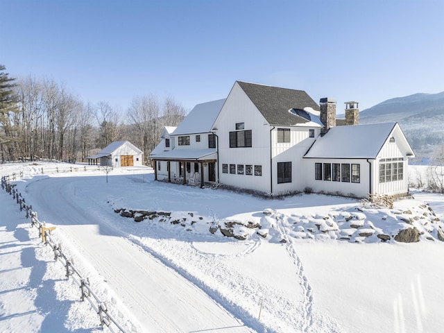 snow covered rear of property with a chimney